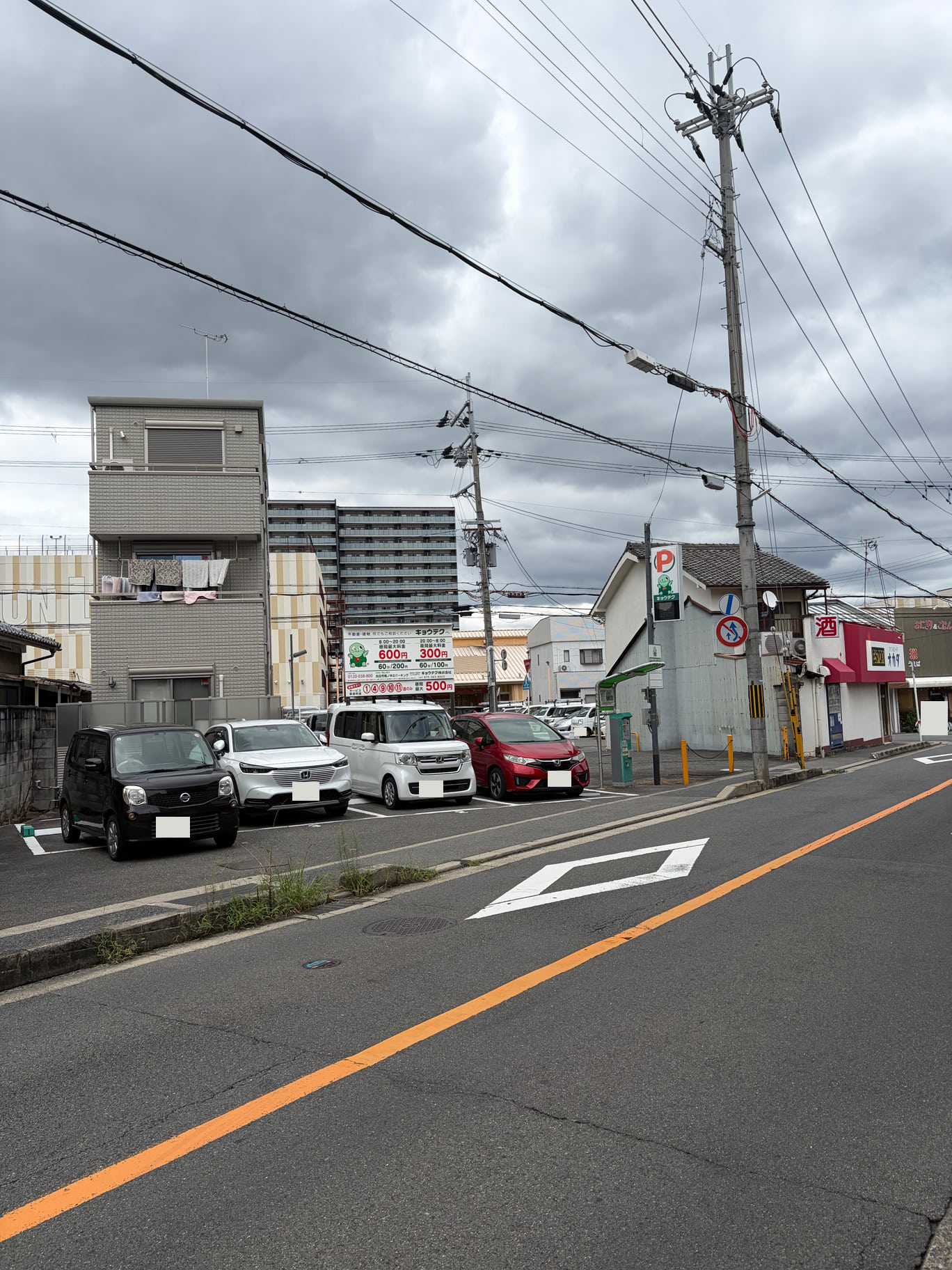 キョウテク駐車場を道路から見た写真。右側の赤いPと緑のキャラクターの看板を赤枠で示しています。